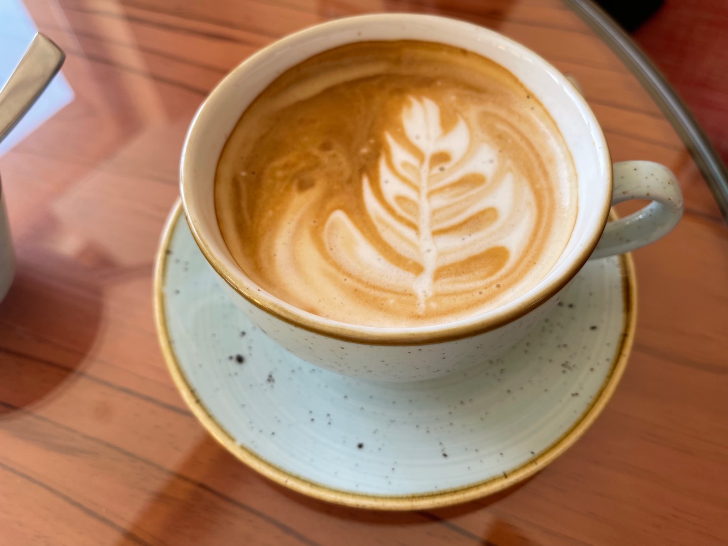 a cup of coffee with a leaf design in the foam