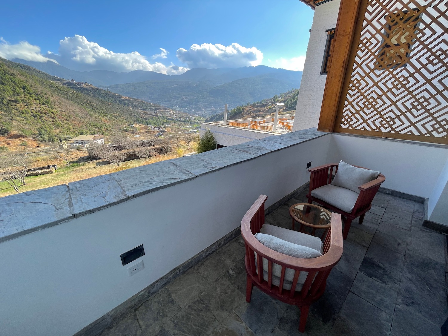 a patio with chairs and a table overlooking a valley