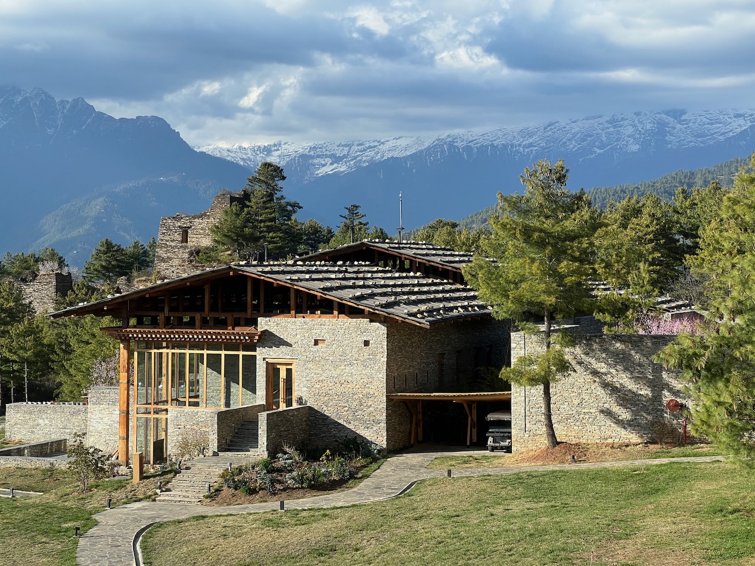 a stone house with trees and mountains in the background