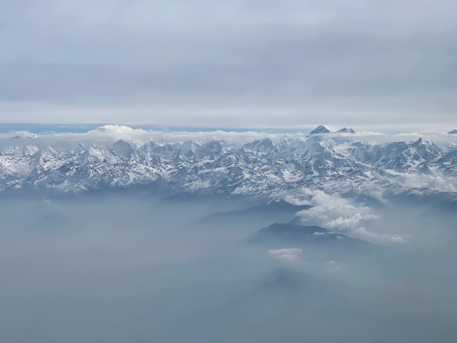 a mountain range with snow and clouds