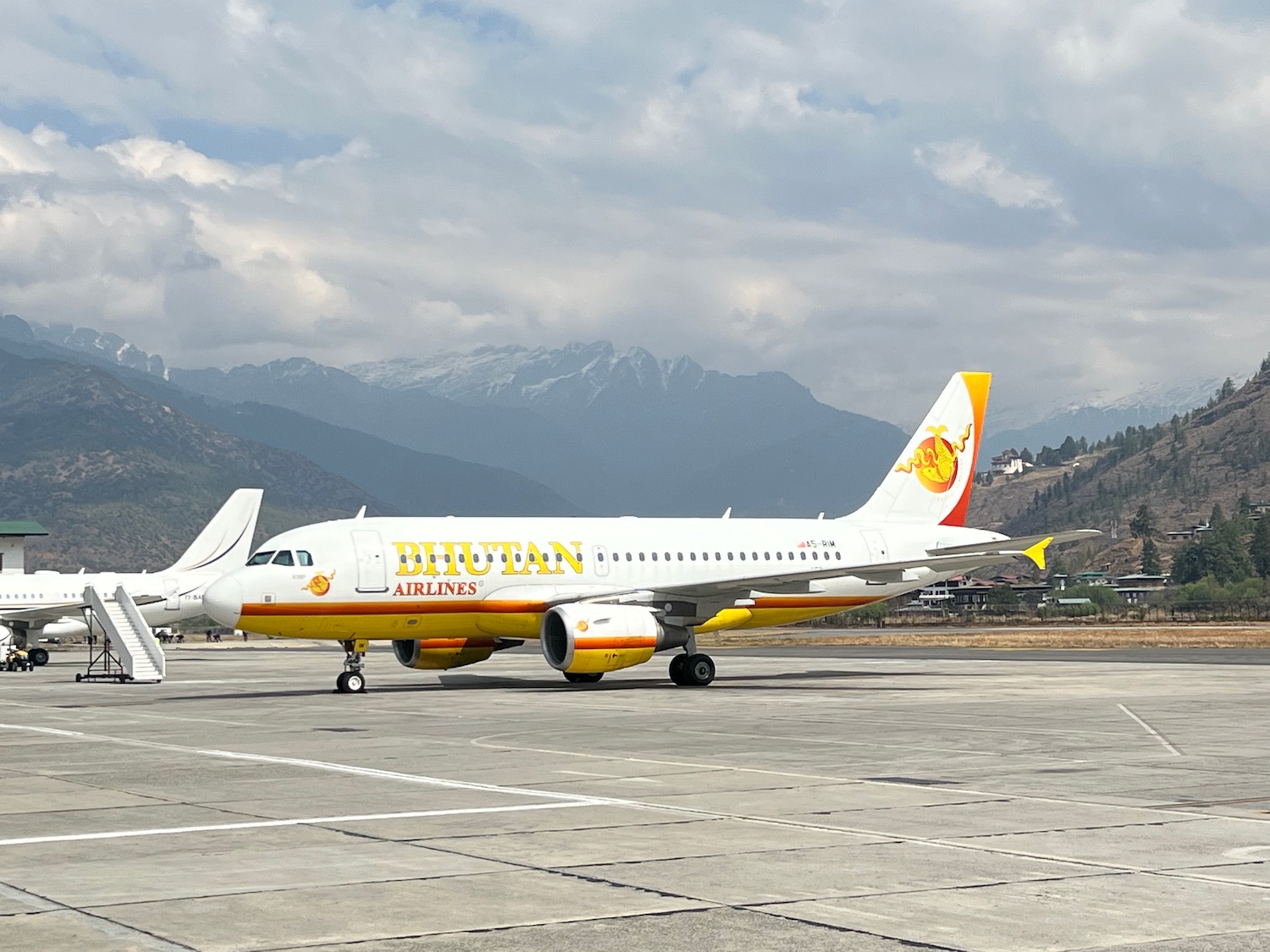 a white and yellow airplane on a runway with mountains in the background