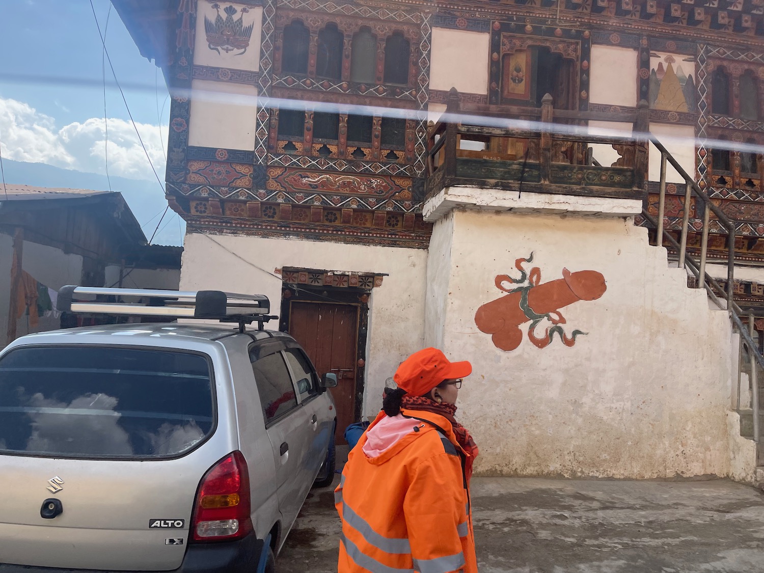 a woman in an orange jacket and cap standing in front of a building