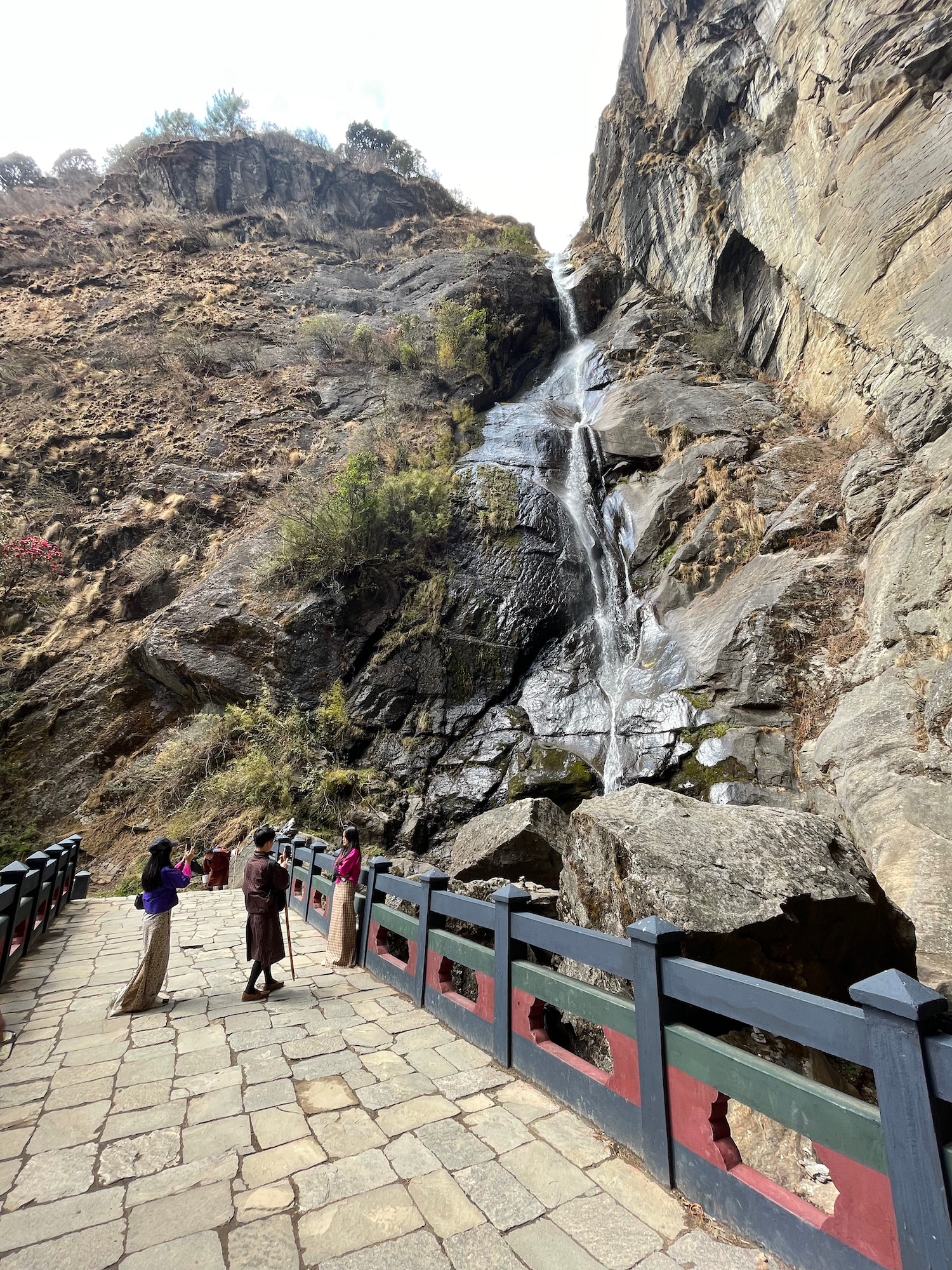 a group of people standing on a bridge near a waterfall