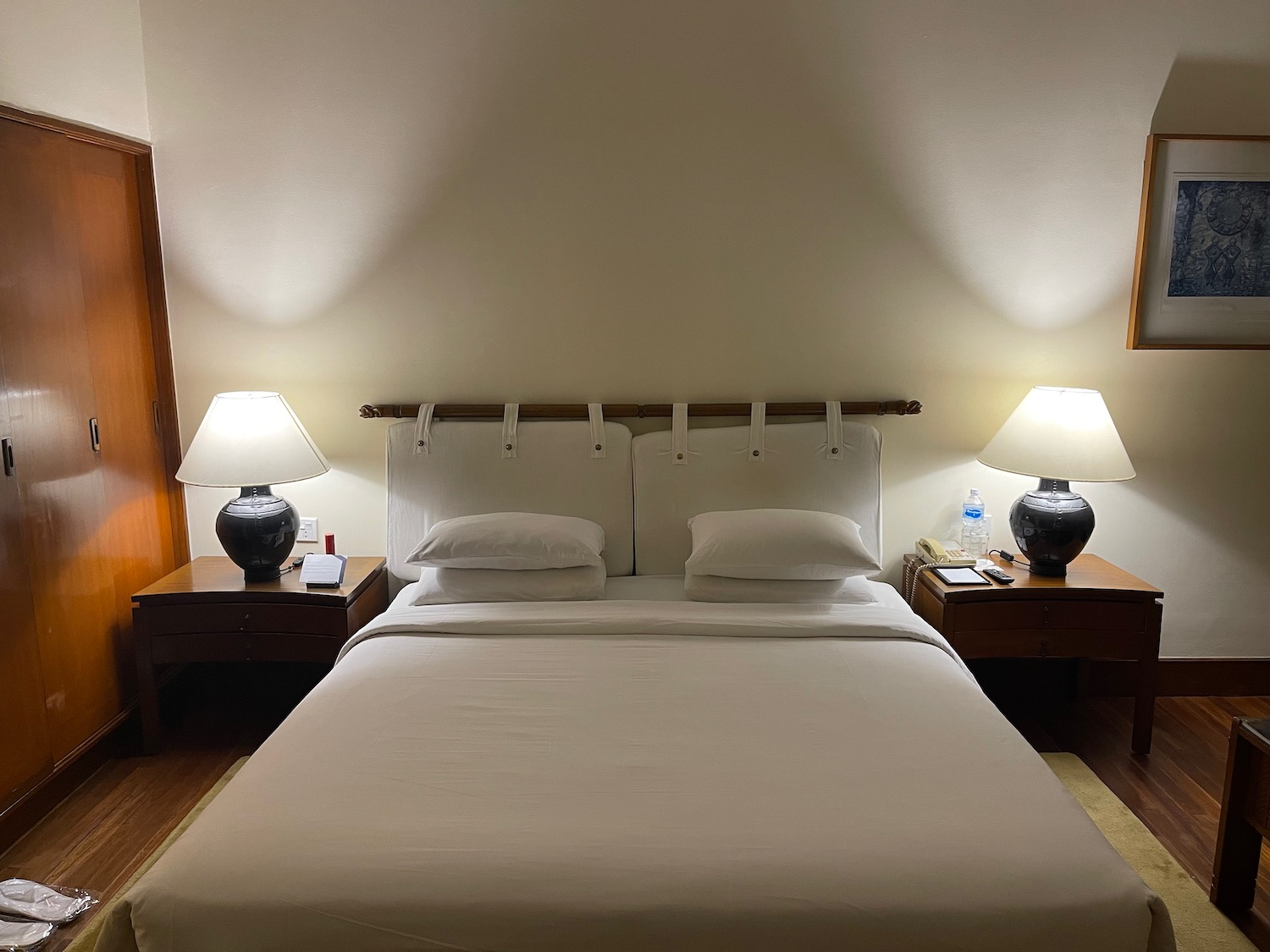 a bed with white sheets and lamps