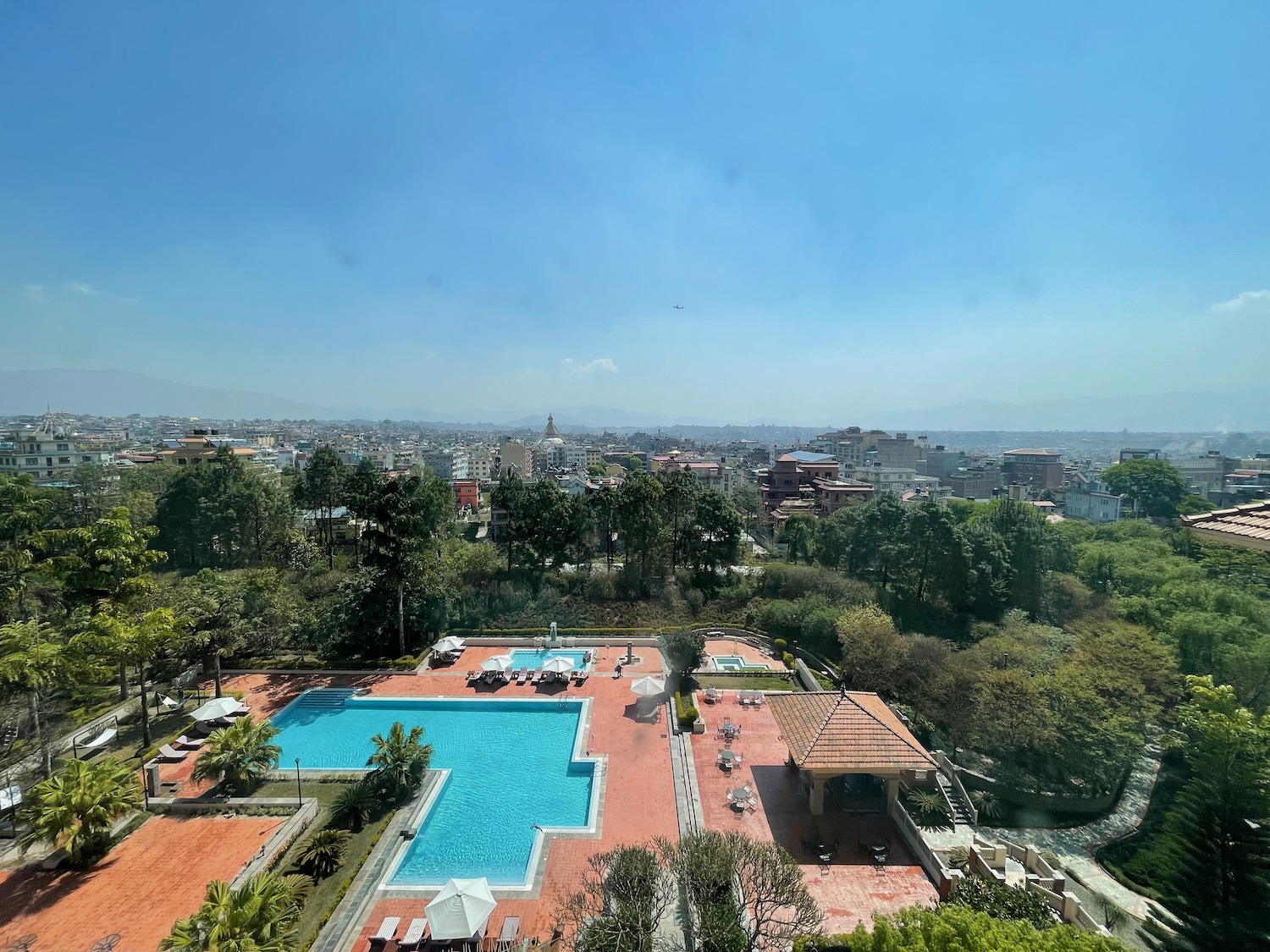 a pool and trees with buildings in the background