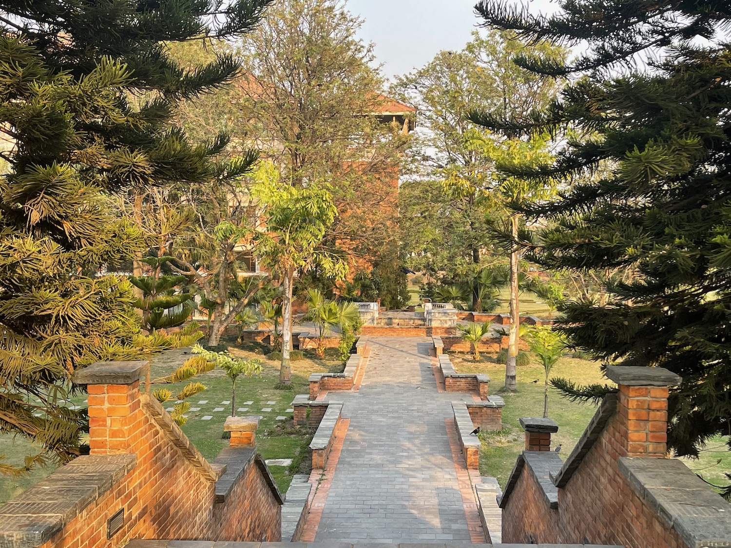 a brick walkway with trees and a building in the background