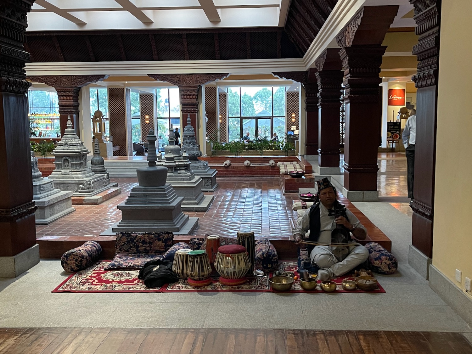 a man playing a musical instrument in a room with many statues