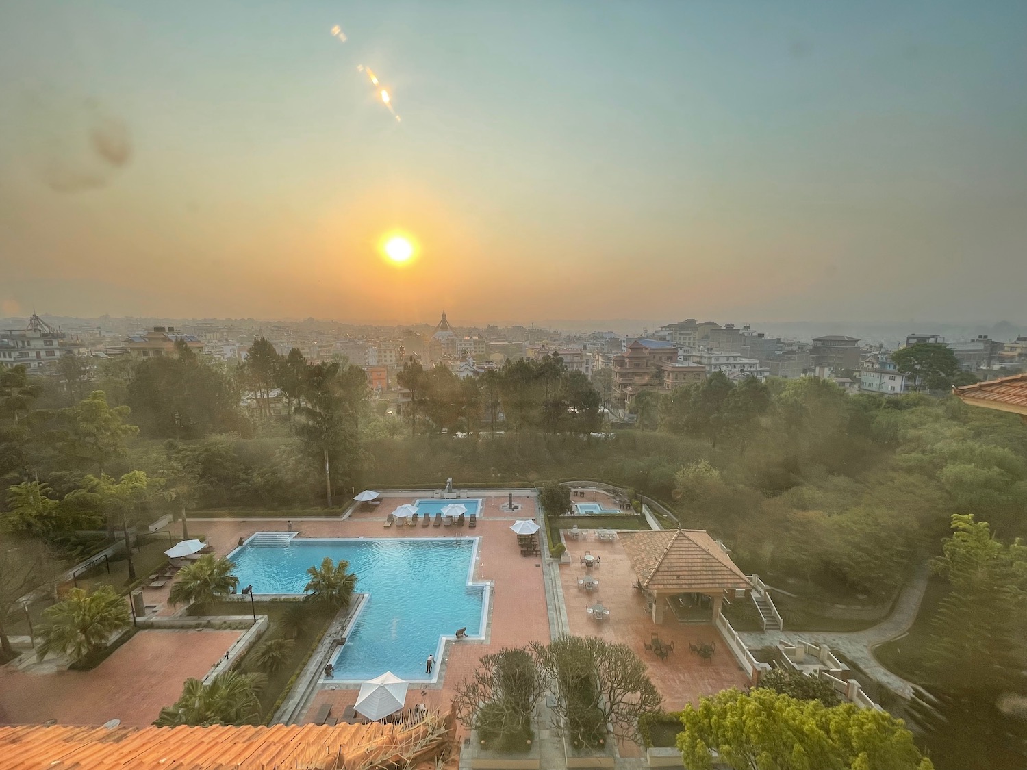 a pool and trees with a city in the background