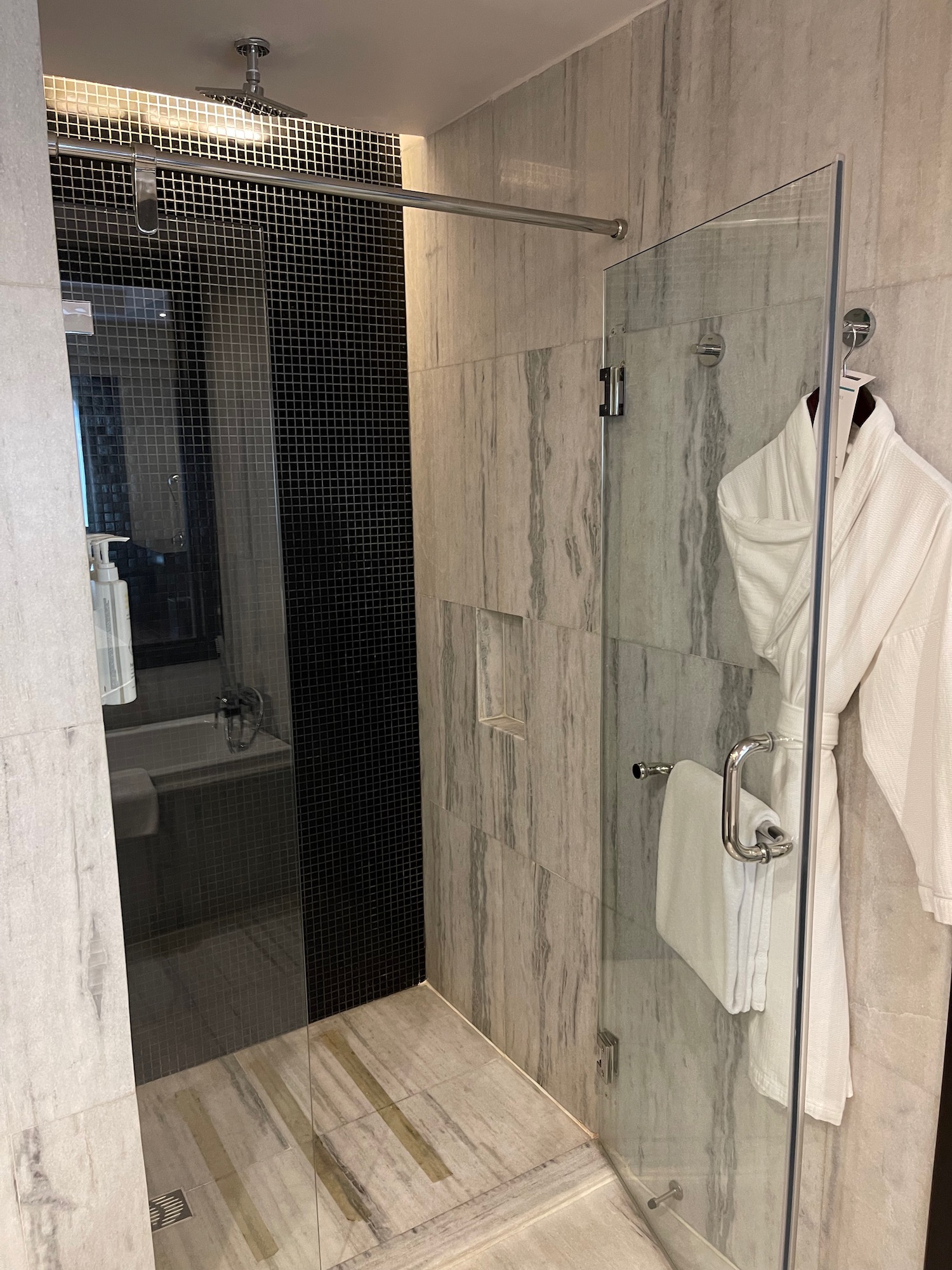 a shower with a white robe and a bathtub