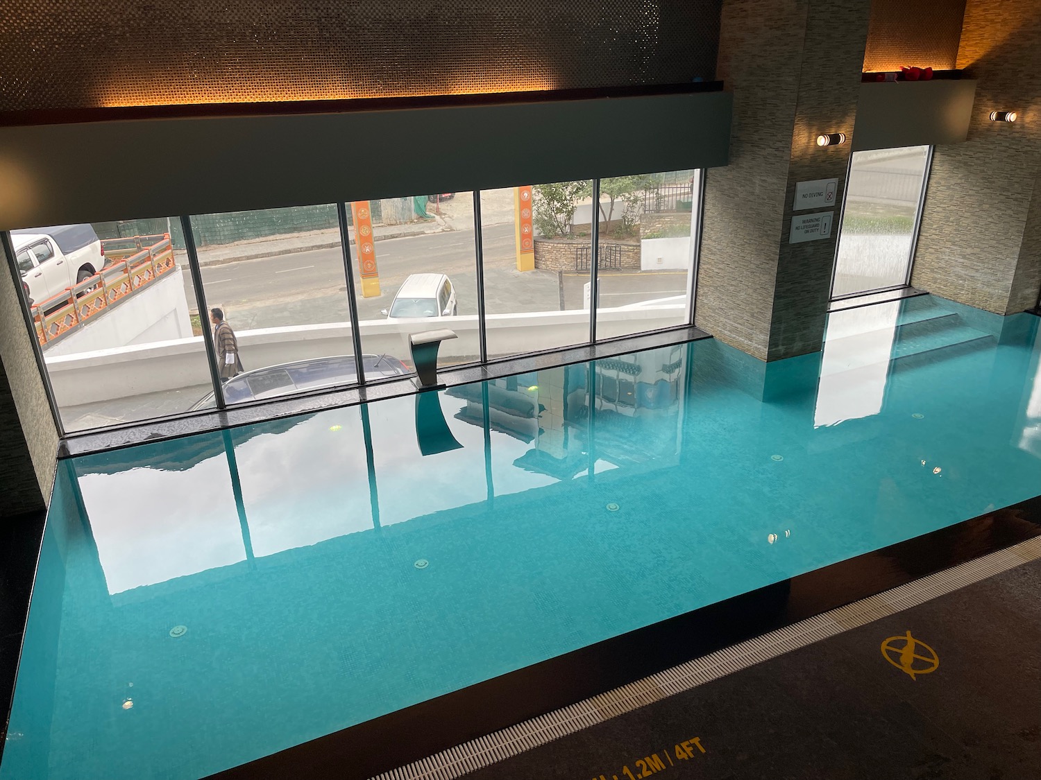 a pool with a glass wall and a car in the background