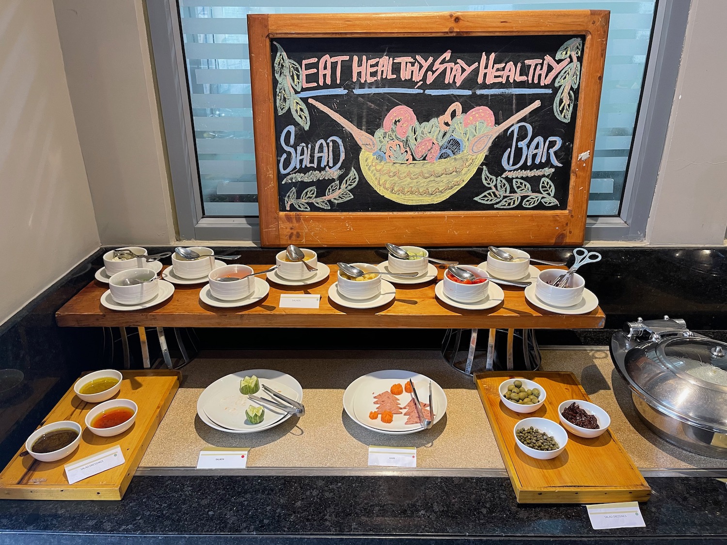 a buffet table with bowls of food and a chalkboard