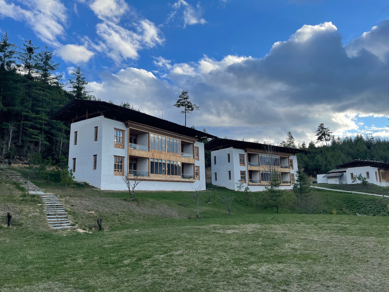 a two white buildings with a green lawn and trees