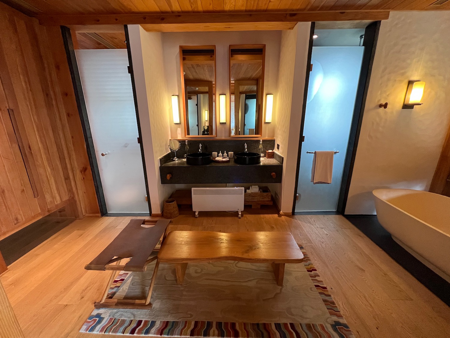 a bathroom with a wood floor and a wood bench