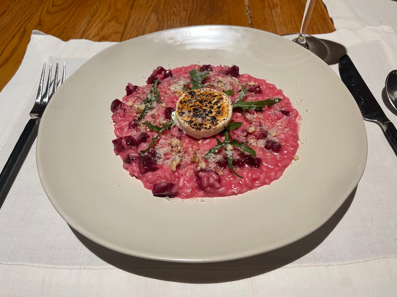 a plate of pink risotto with a goat cheese on top