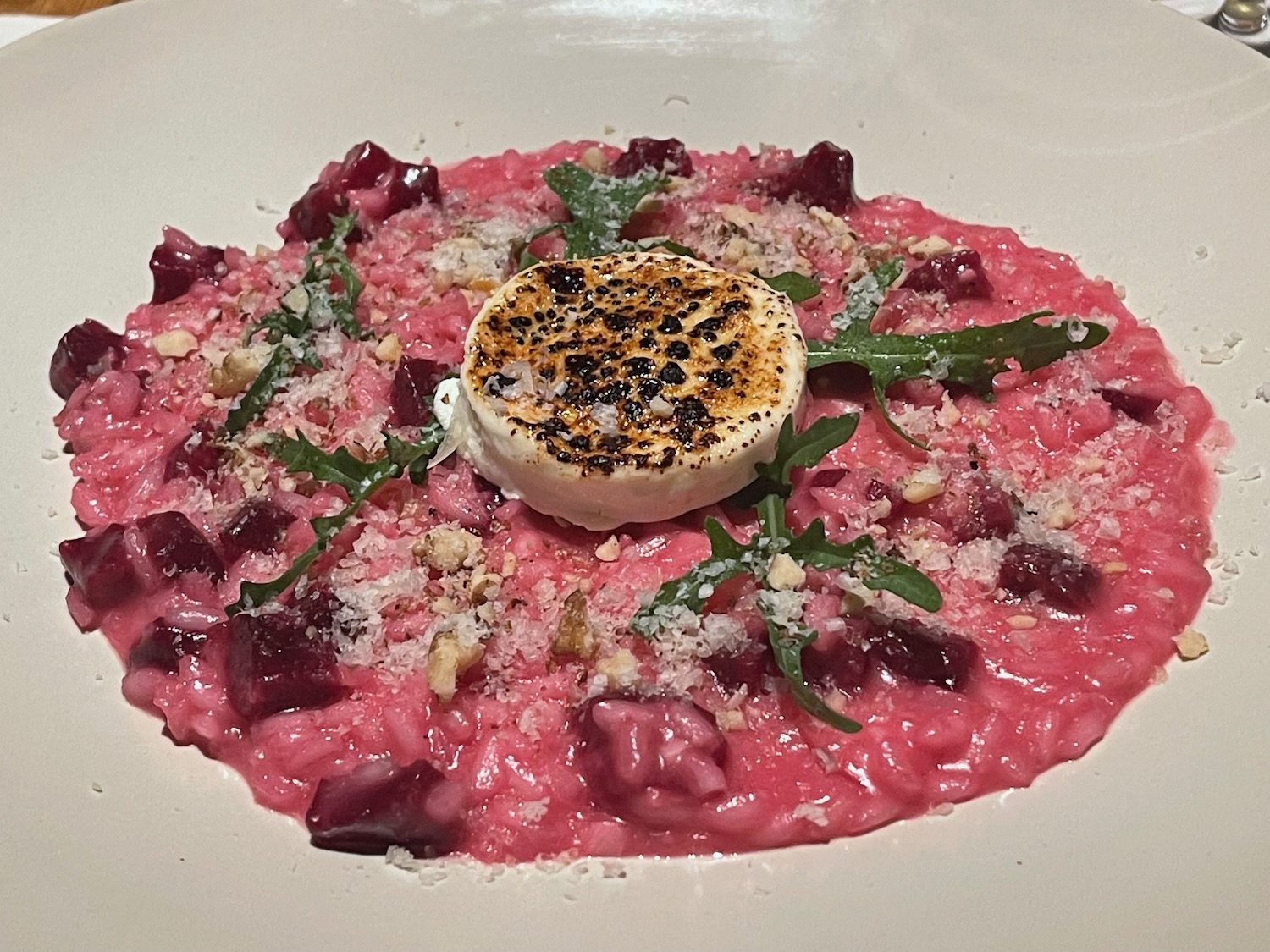 a plate of pink risotto with a goat cheese on top