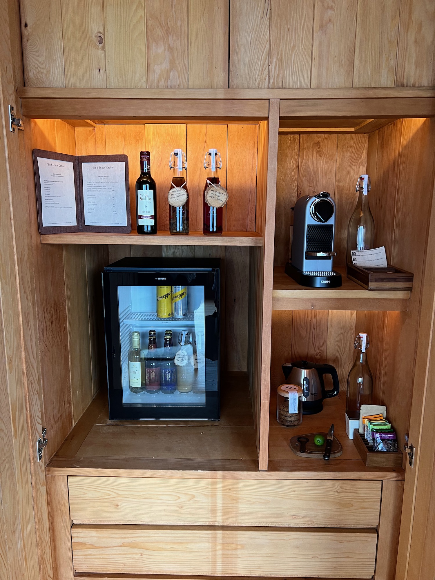 a cabinet with a mini fridge and bottles of alcohol