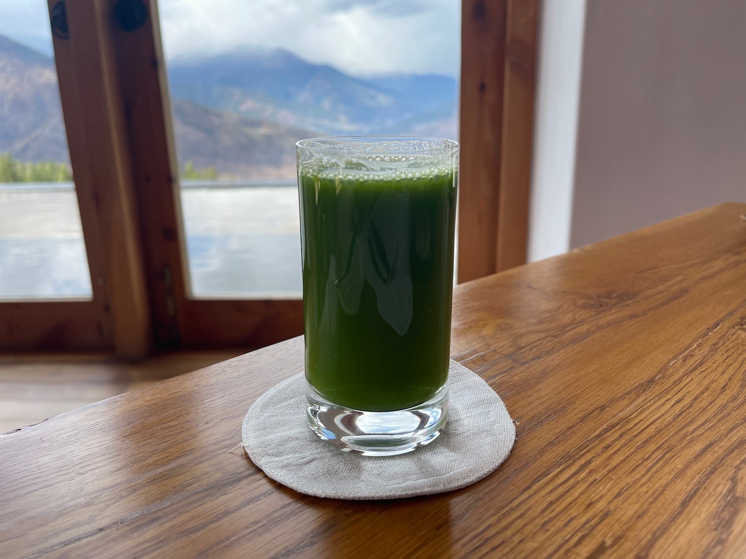 a glass of green juice on a table