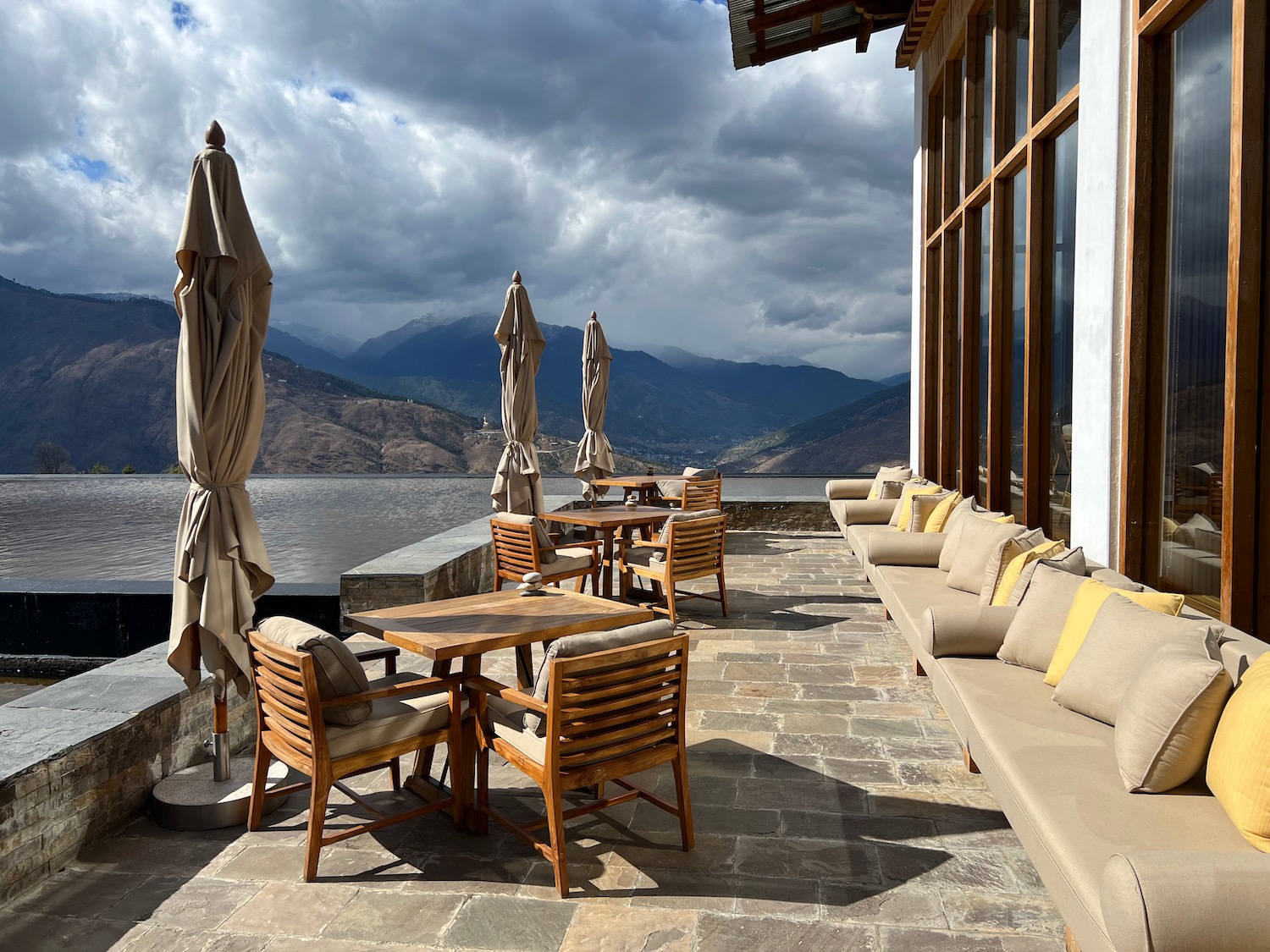 a patio with chairs and umbrellas by a lake