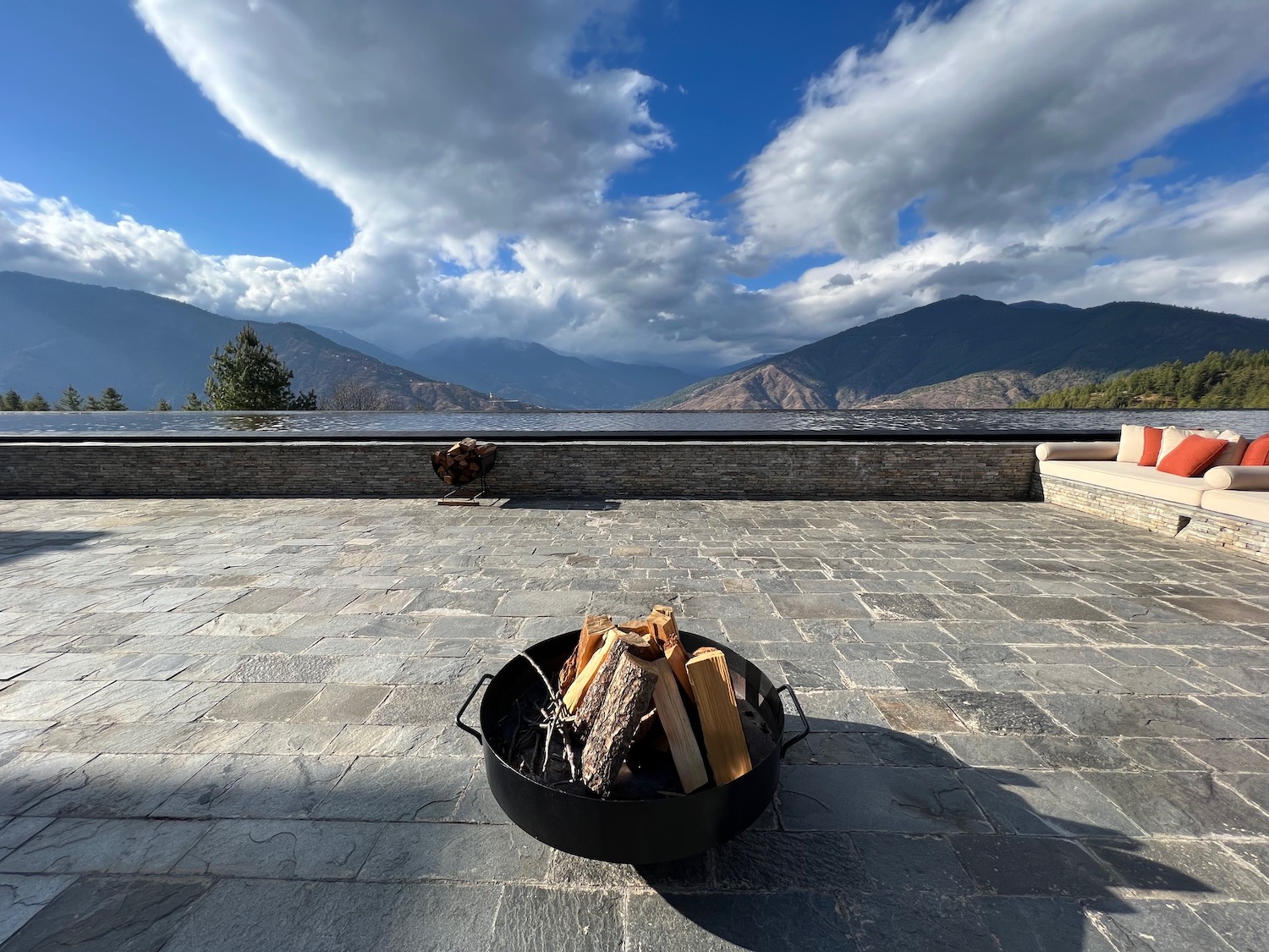 a fire pit on a stone patio with mountains in the background