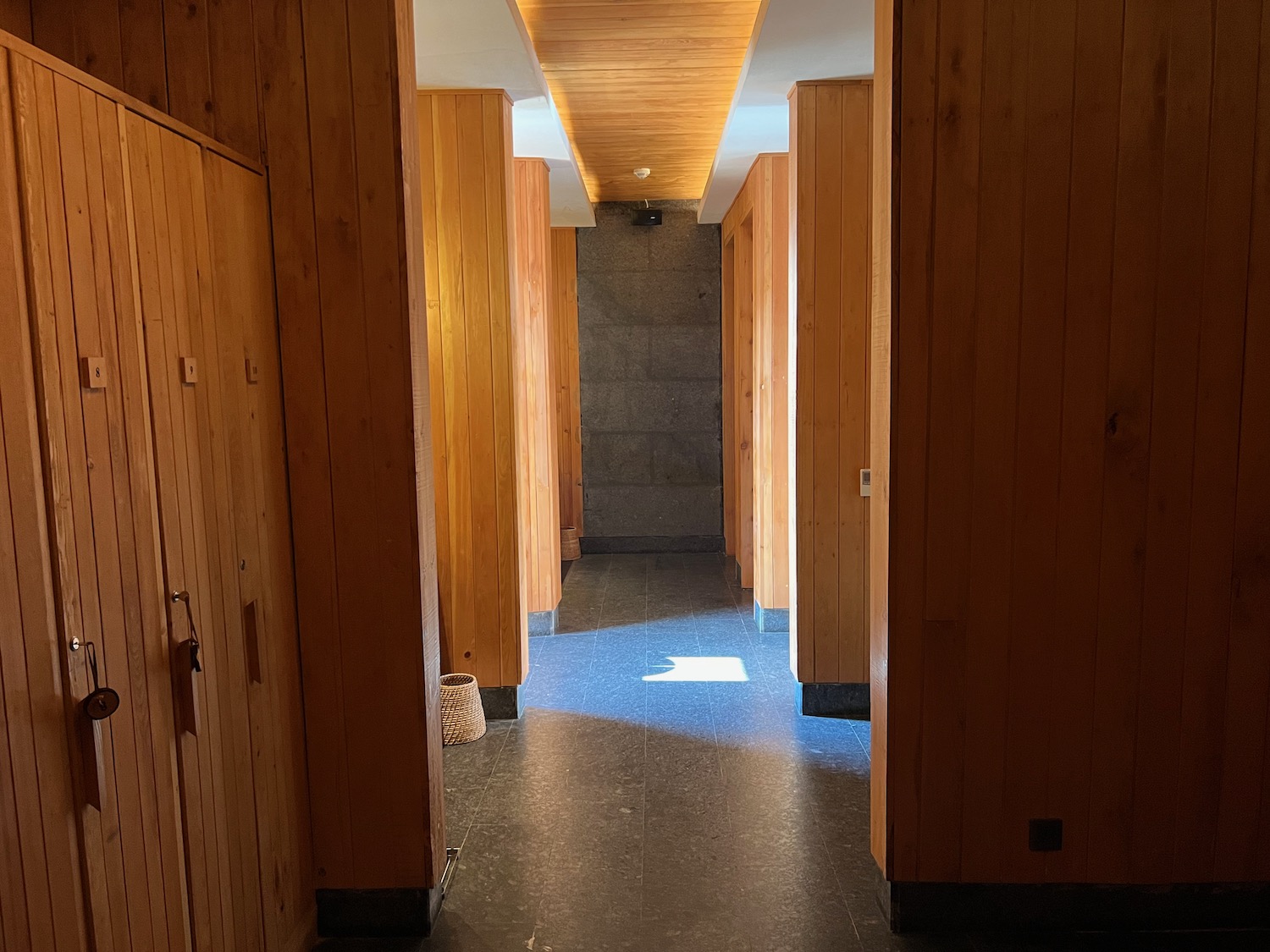 a hallway with wood walls and a stone wall