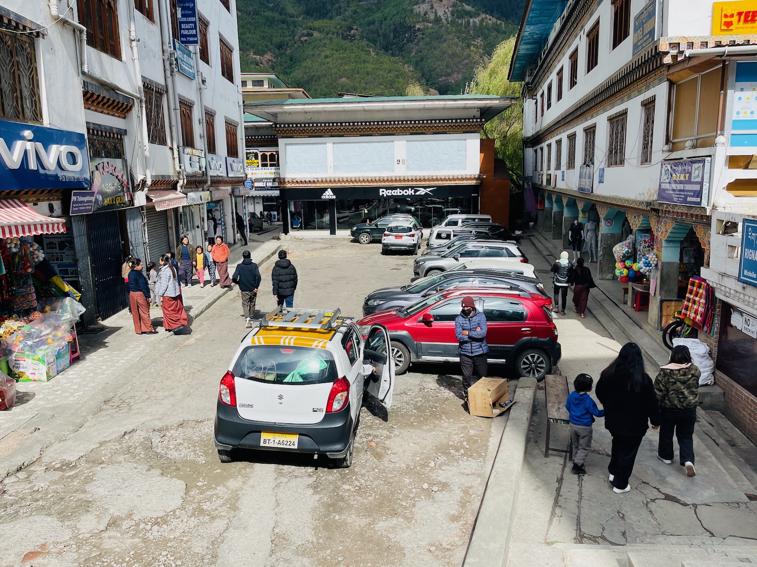 a group of people standing in a street with cars parked