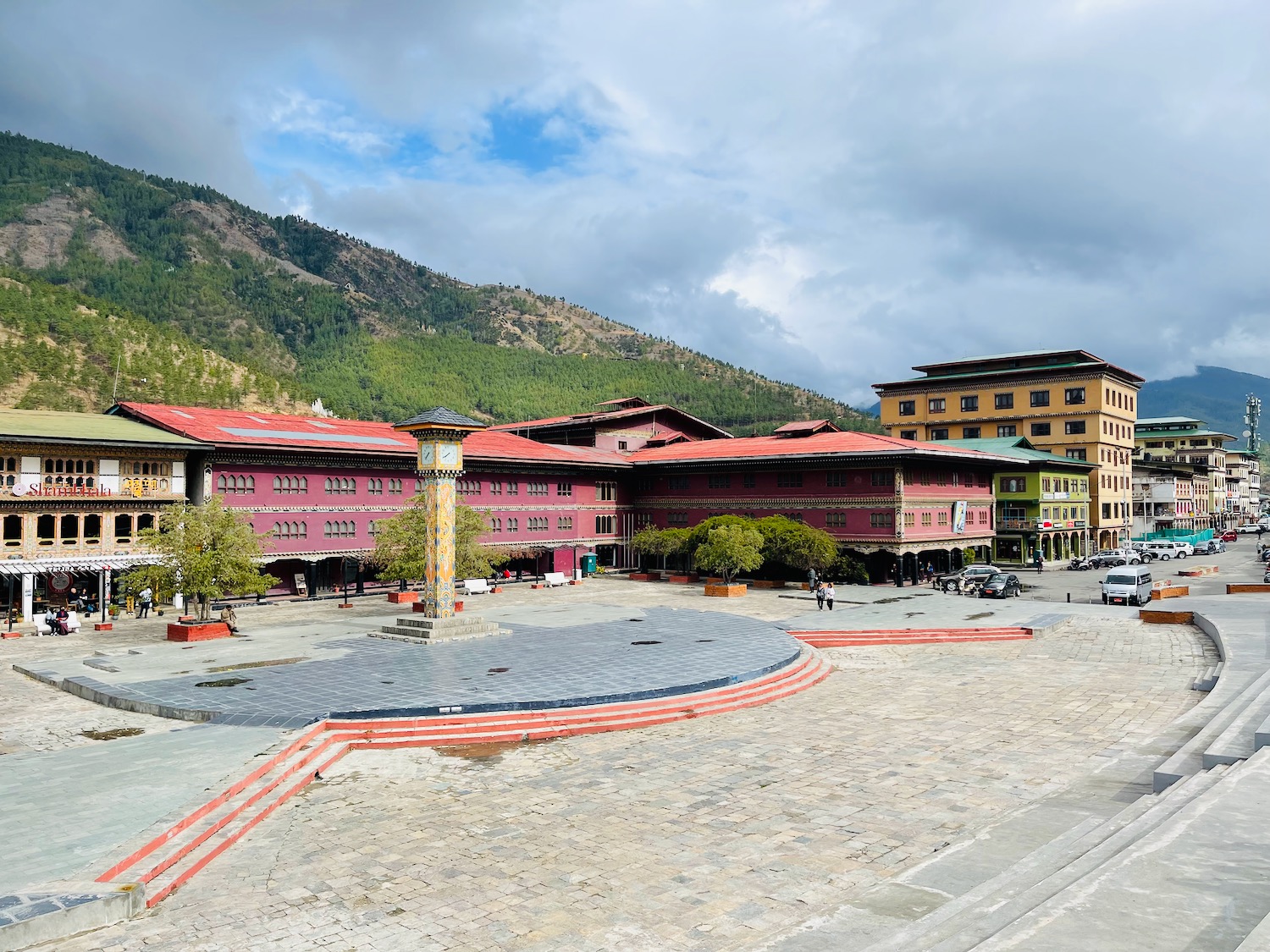 a large square with buildings and Punakha Dzong in the background