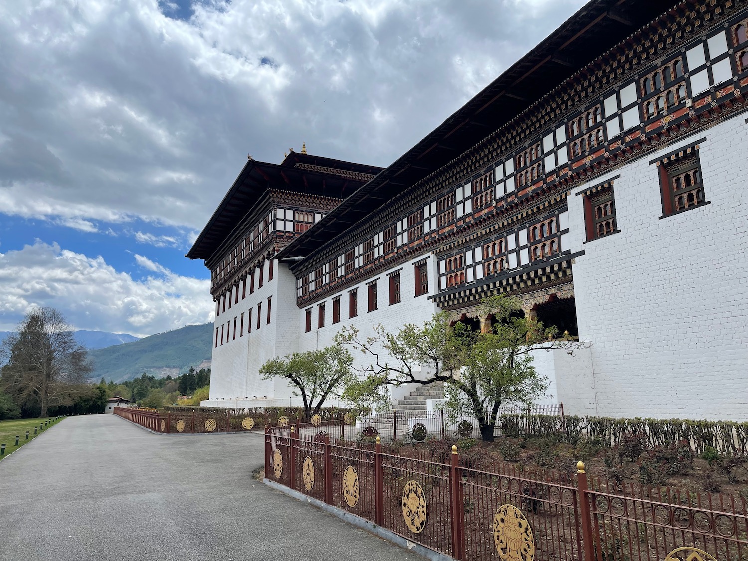 a white building with a fence and mountains in the background