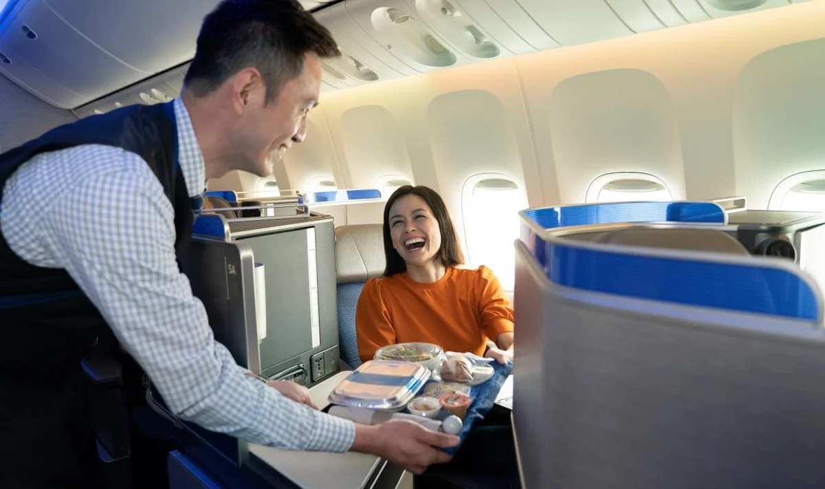 a man and woman smiling while sitting in an airplane