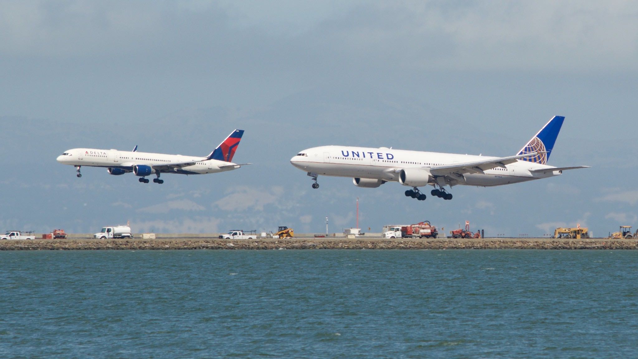 two airplanes flying over water