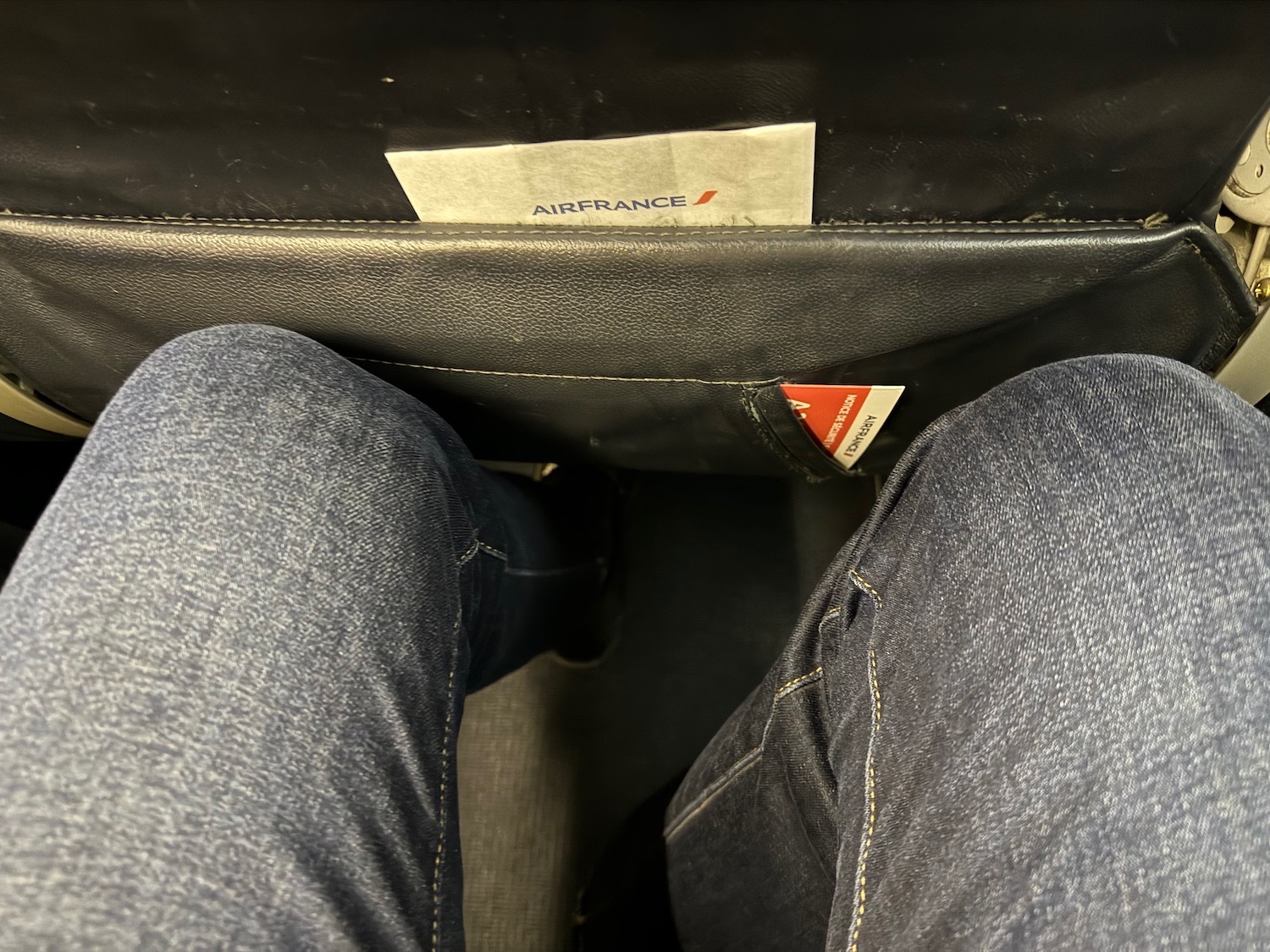 a person's legs in jeans and a piece of paper in a seat