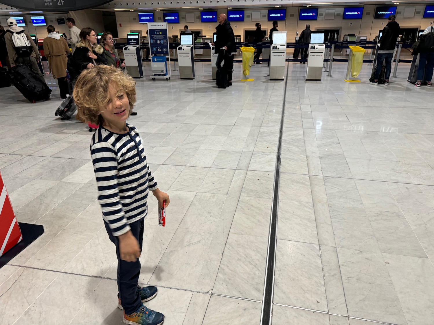 a child standing in a room with people behind them