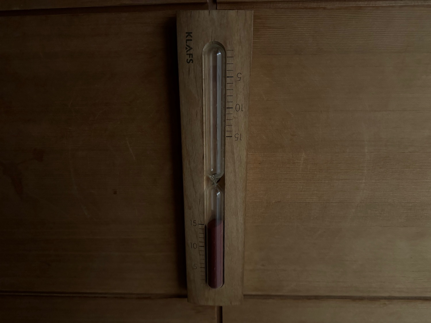 a wooden hourglass with a red sand in it