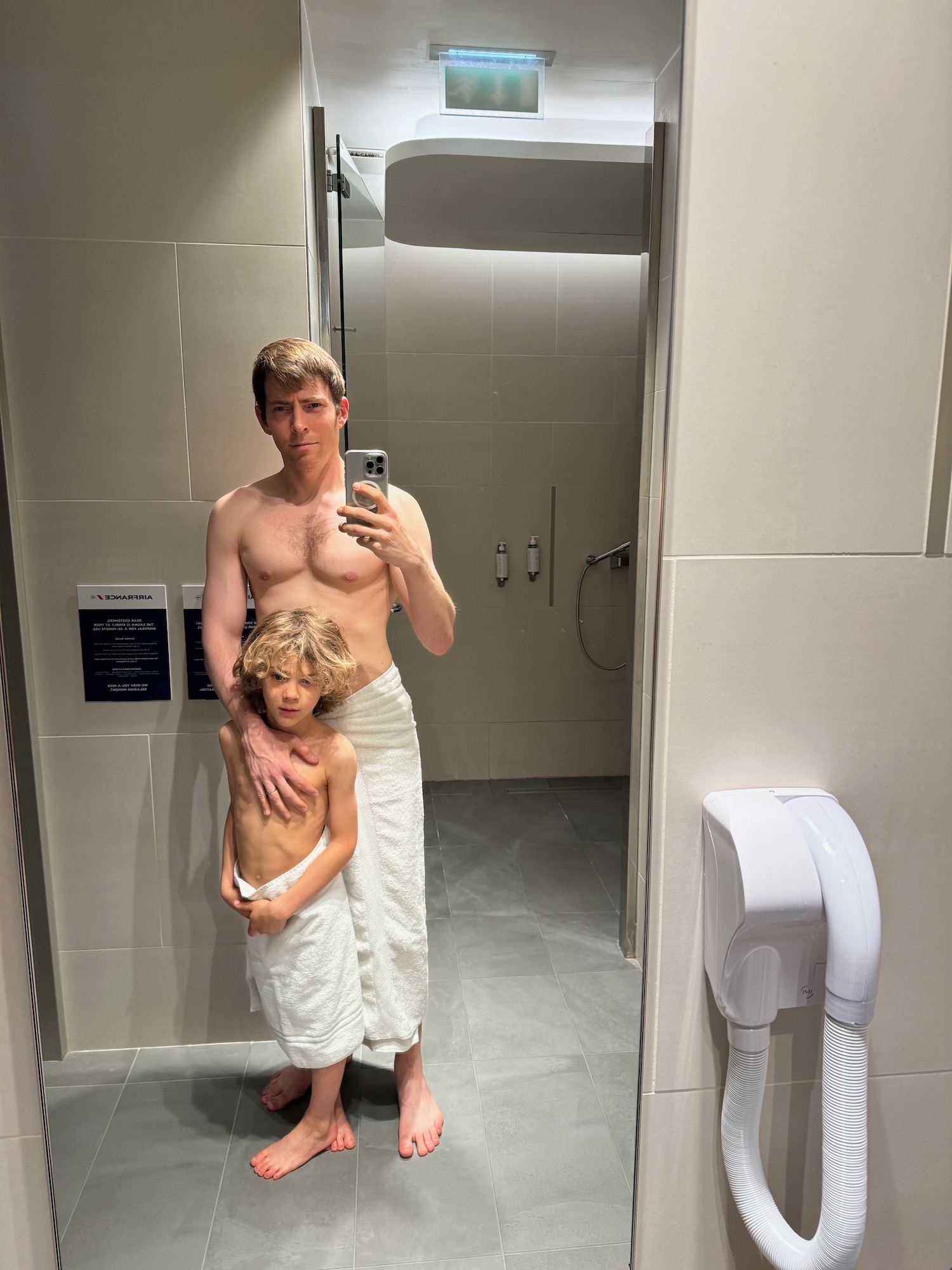 a man taking a selfie with a boy in a bathroom