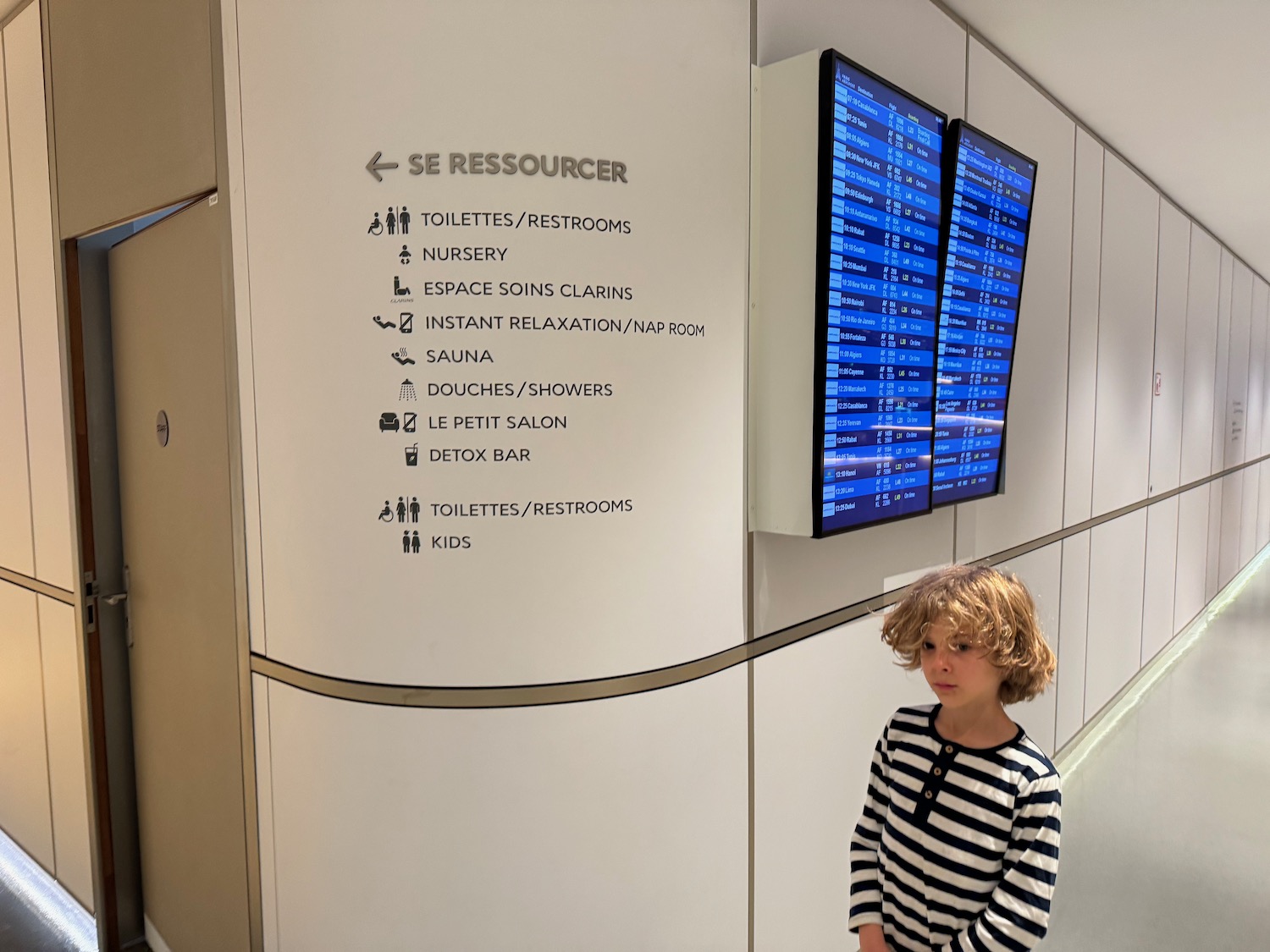 a child standing in front of a wall with information screens