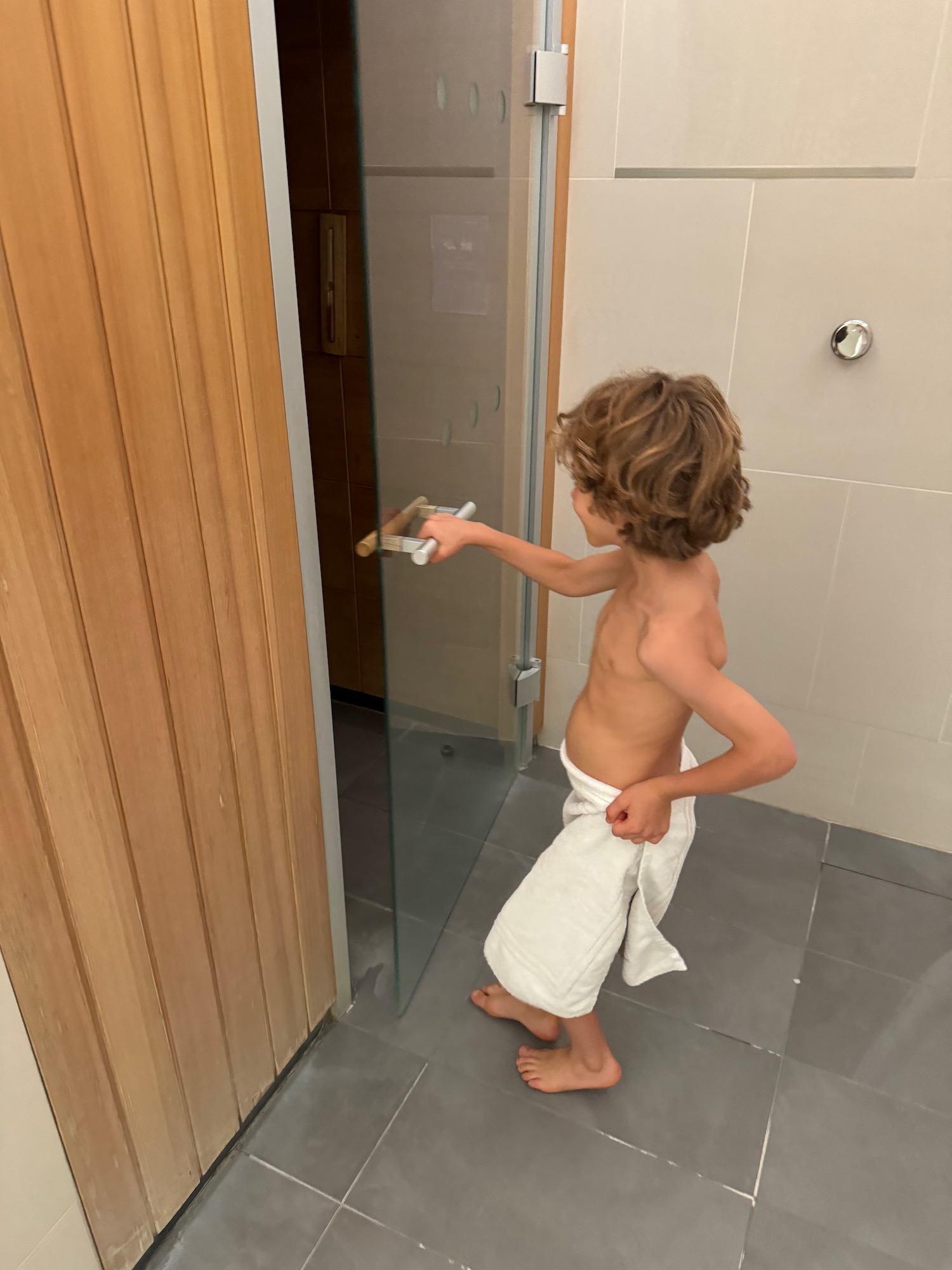 a boy in a towel holding a brush in a shower