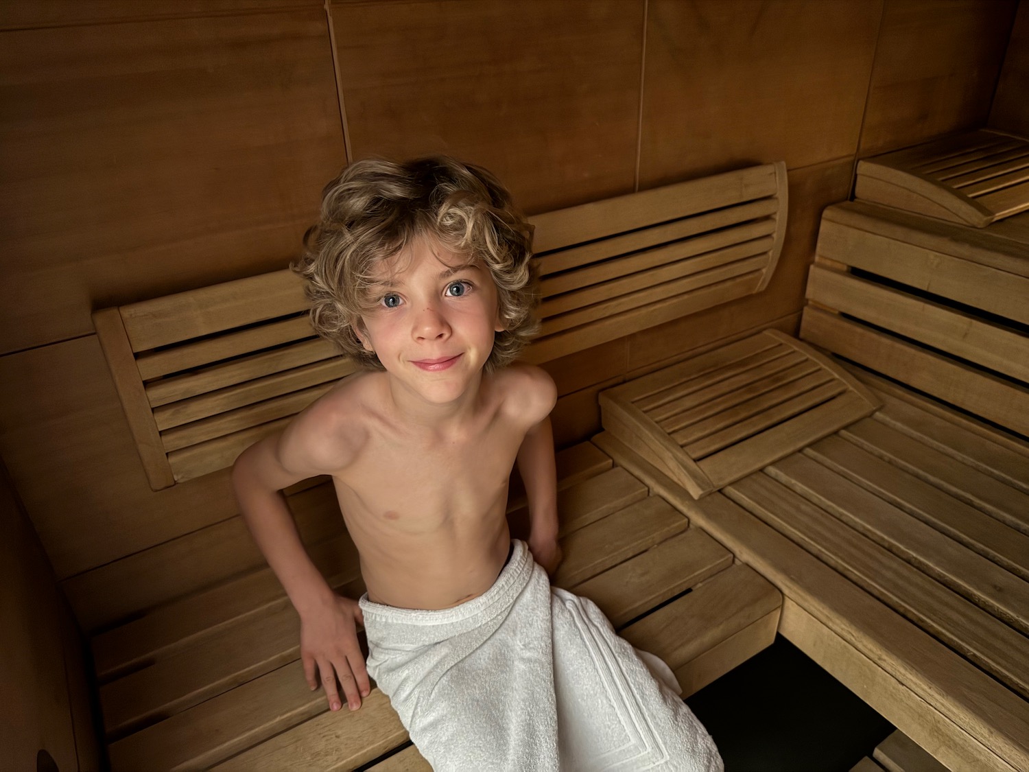 a boy sitting on a bench in a sauna