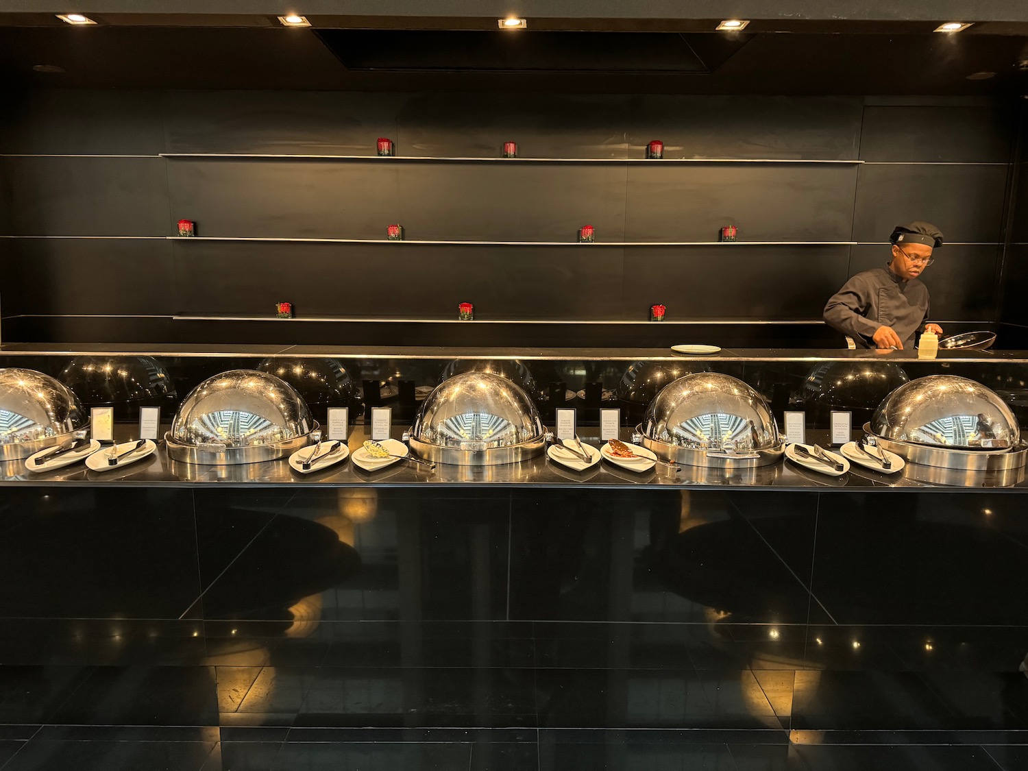 a man standing behind a counter with silver bowls on it