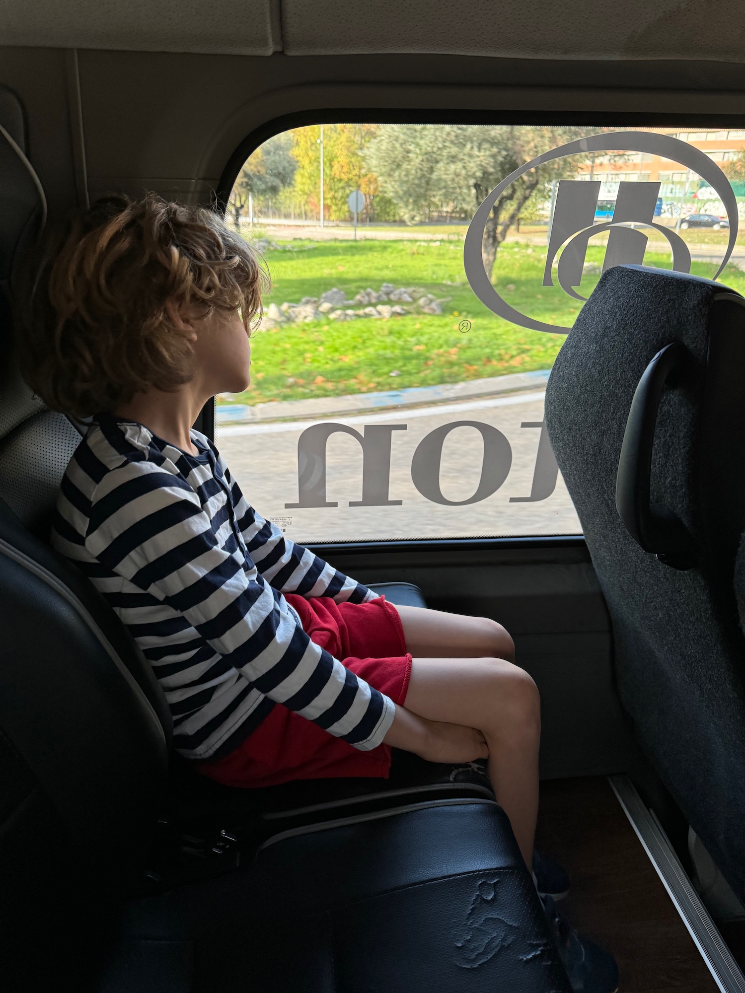 a child sitting in a bus looking out a window