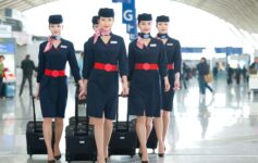 a group of women wearing uniforms and holding luggage