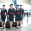 a group of women wearing uniforms and holding luggage