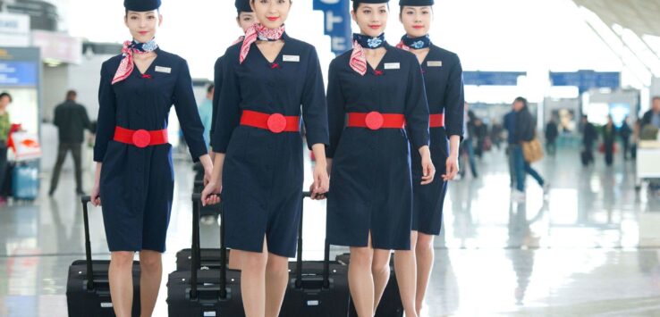 a group of women wearing uniforms and holding luggage