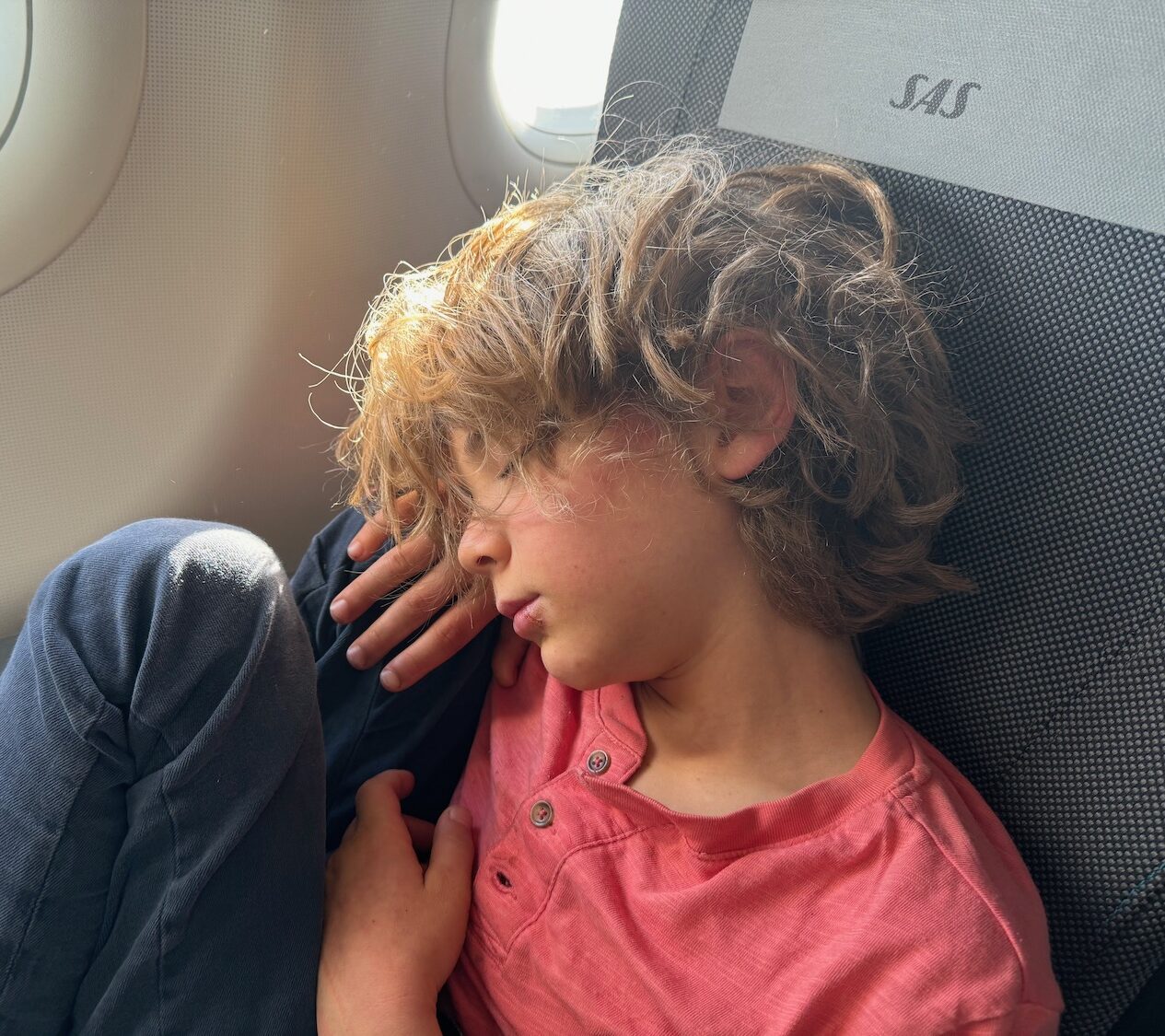 a boy sleeping on an airplane