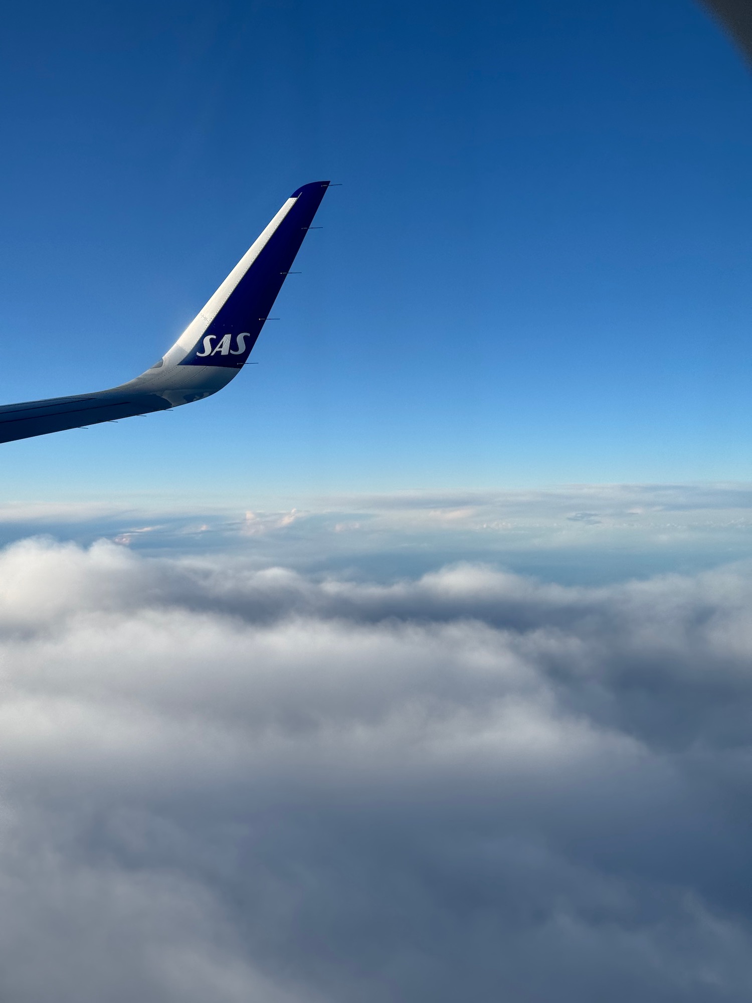 an airplane wing with clouds in the background