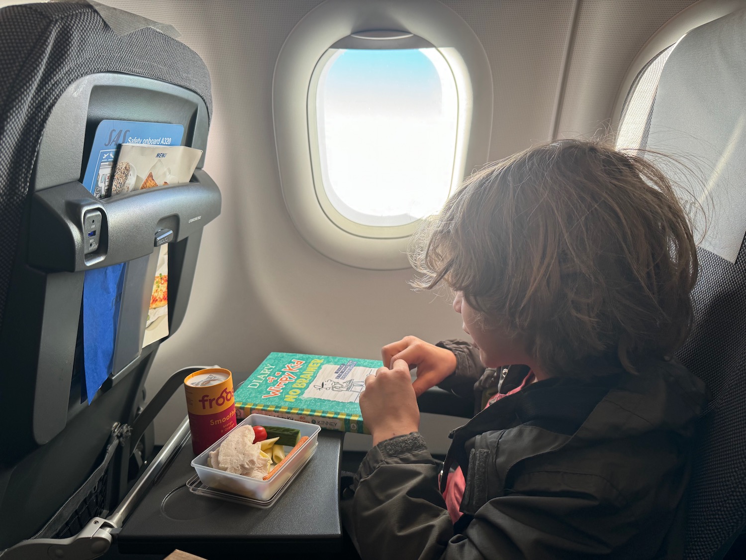 a child sitting at a table in an airplane