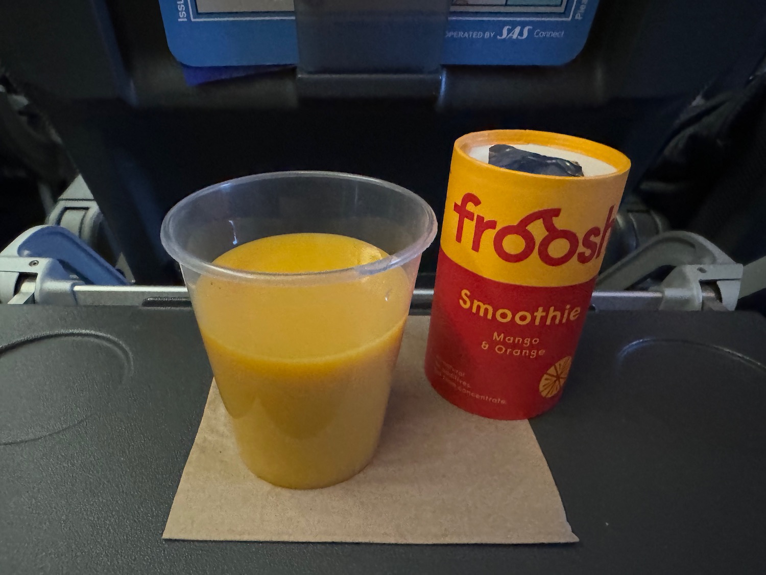 a cup of orange juice and a container of yogurt on a napkin