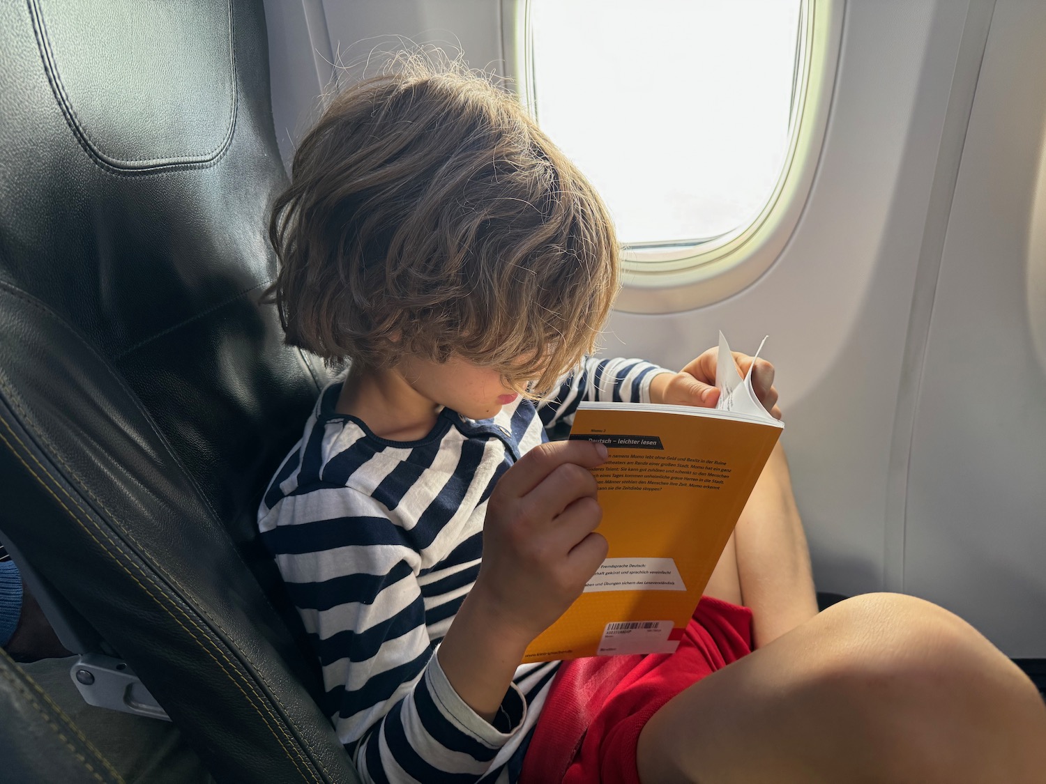 a child reading a book on an airplane