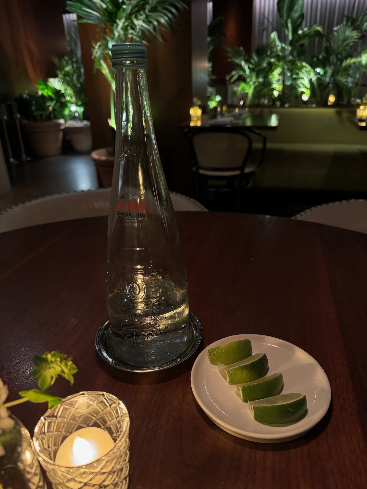 a glass bottle and lime slices on a plate