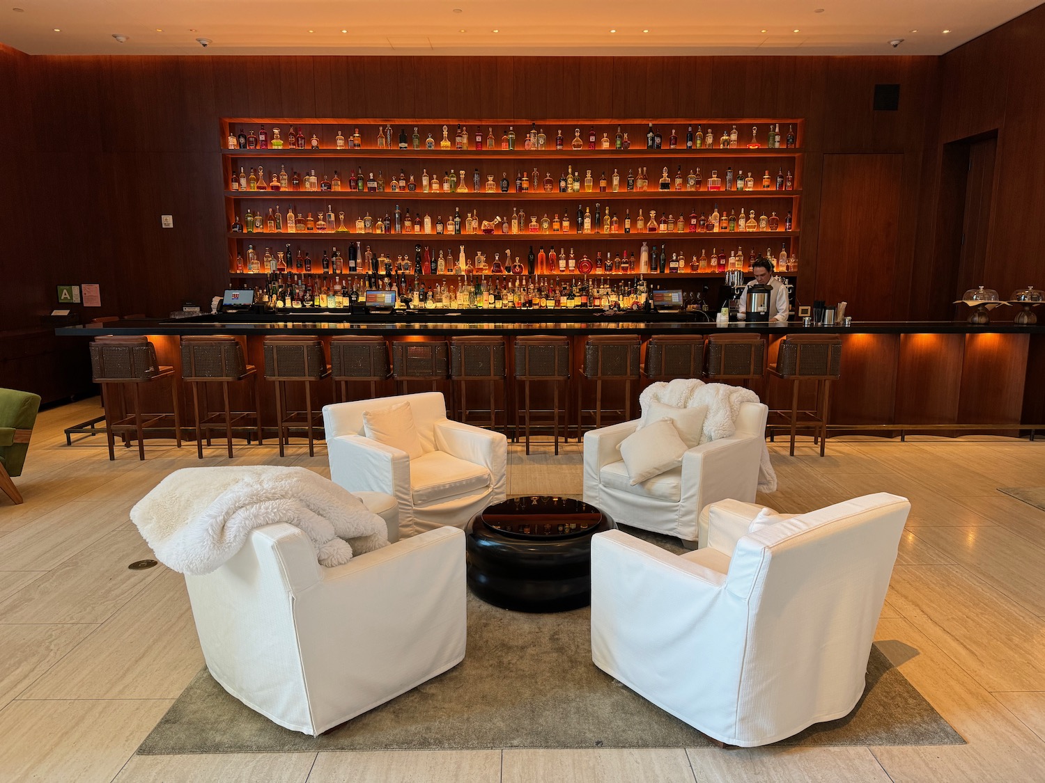 a room with a bar and a bar with white chairs and a bar with bottles