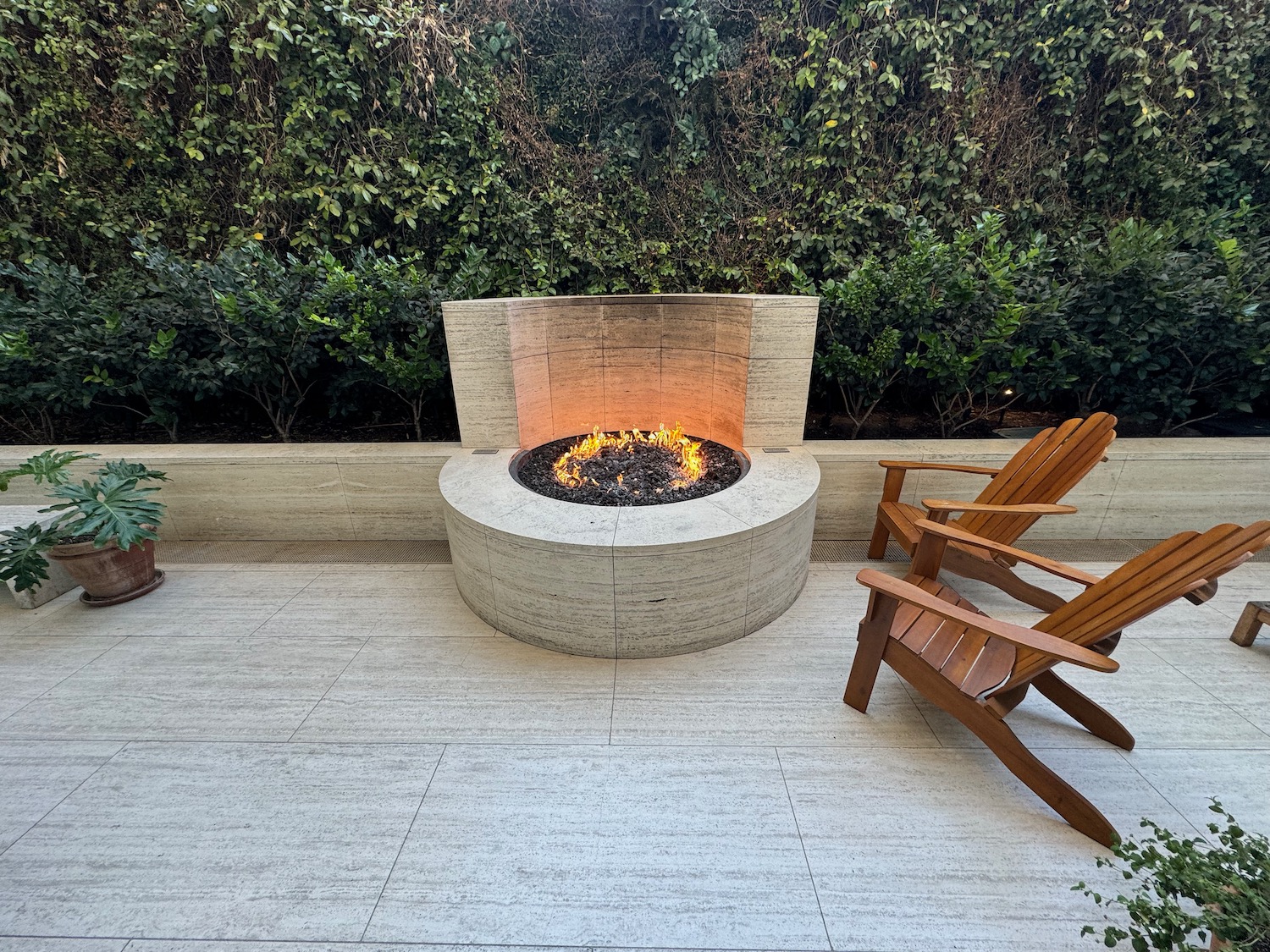 a fire pit with a wood chair in front of a bush