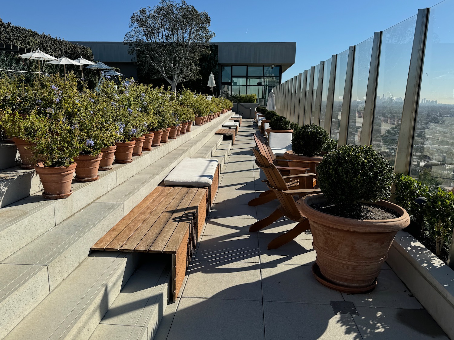 a terrace with a bench and chairs and potted plants